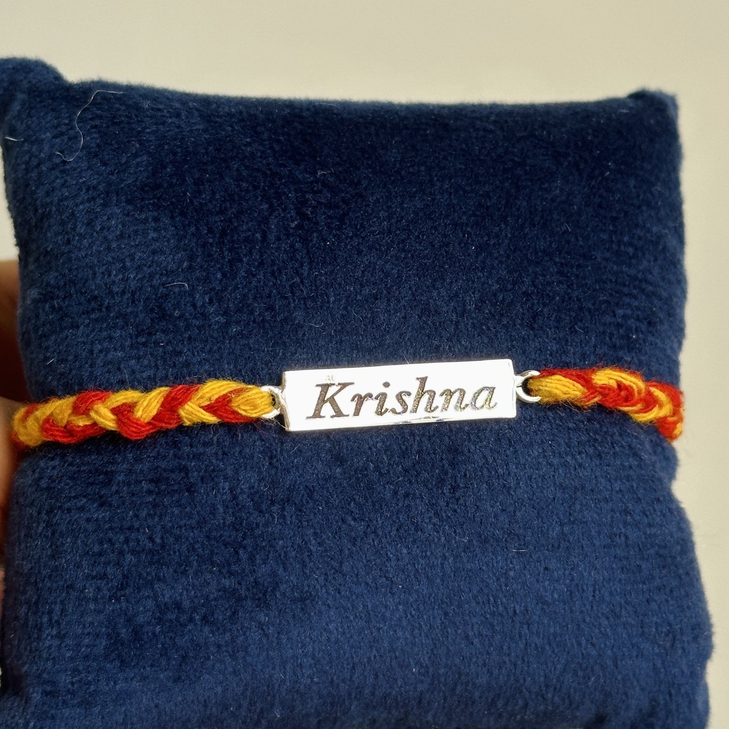 personalized name rakhi close-up — engraved silver name plate detail