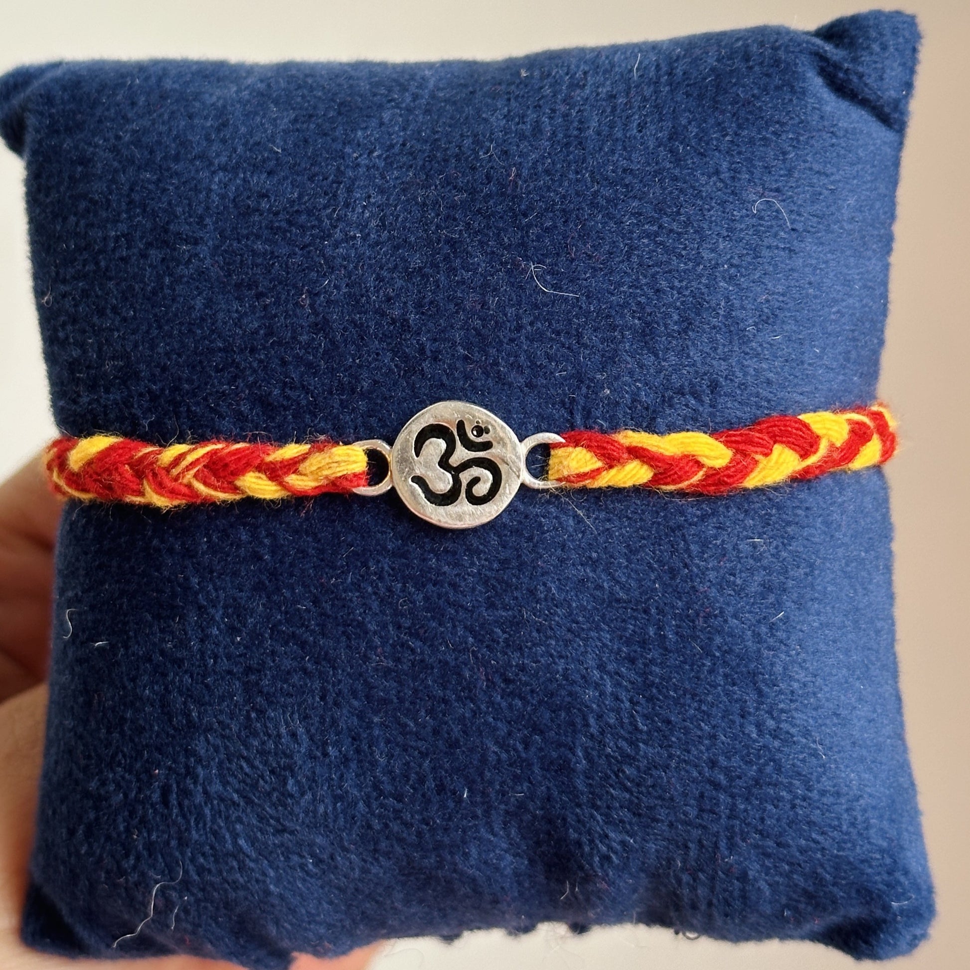Mahadev Om Rakhi close-up — silver Om symbol detail on festive thread