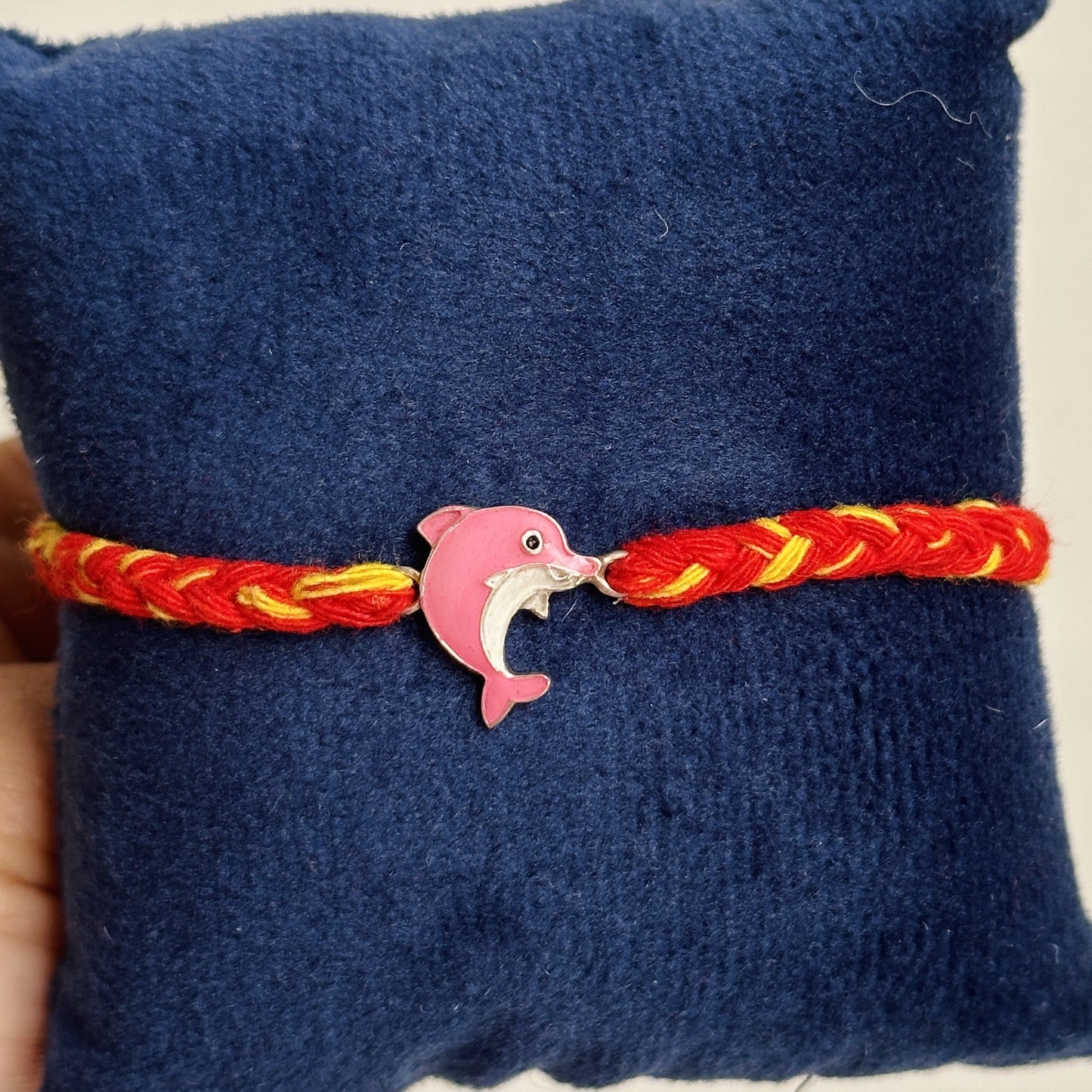 dolphin charm rakhi close-up — enamel dolphin motif detail