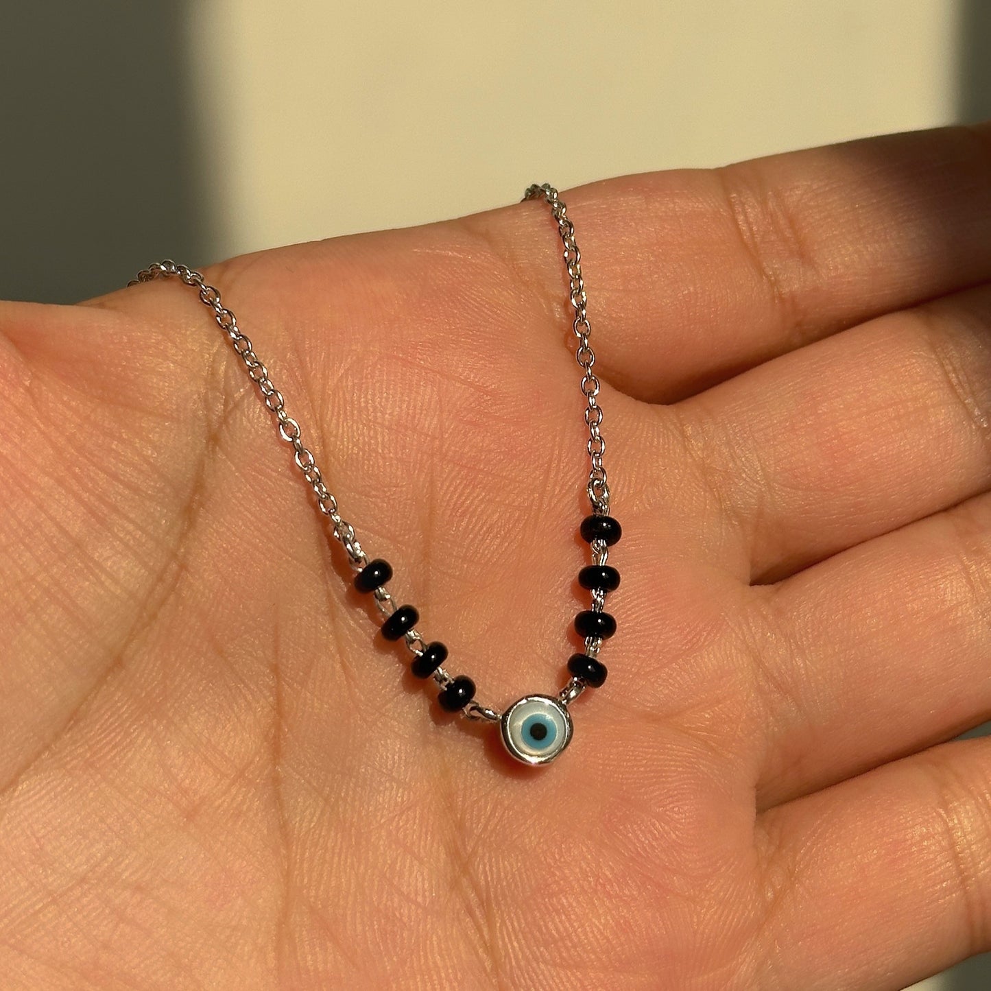 evil eye essence mangalsutra close-up — blue evil eye charm detail