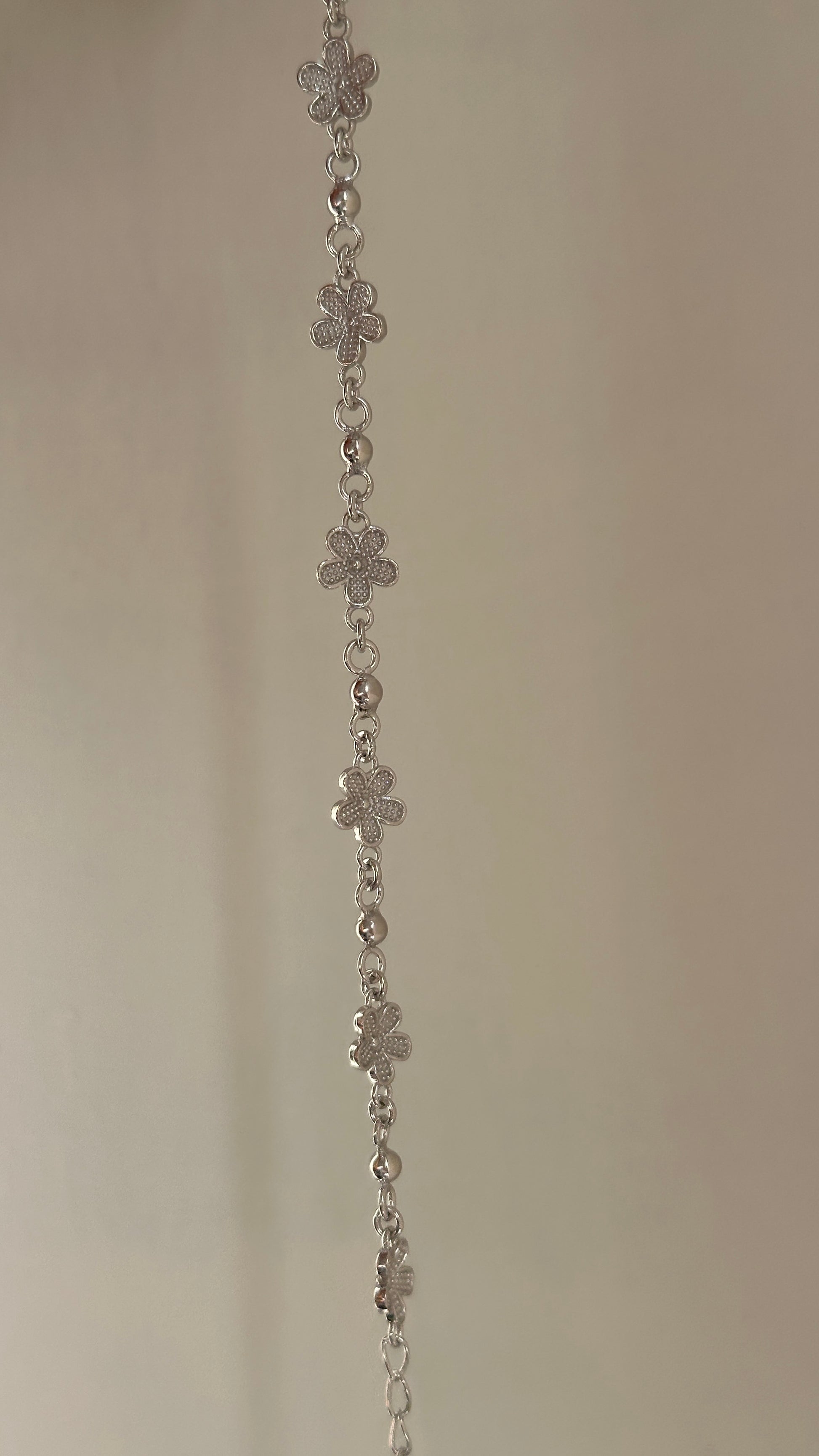 Mini Bloom Bracelet close-up — delicate silver flower detail on fine chain